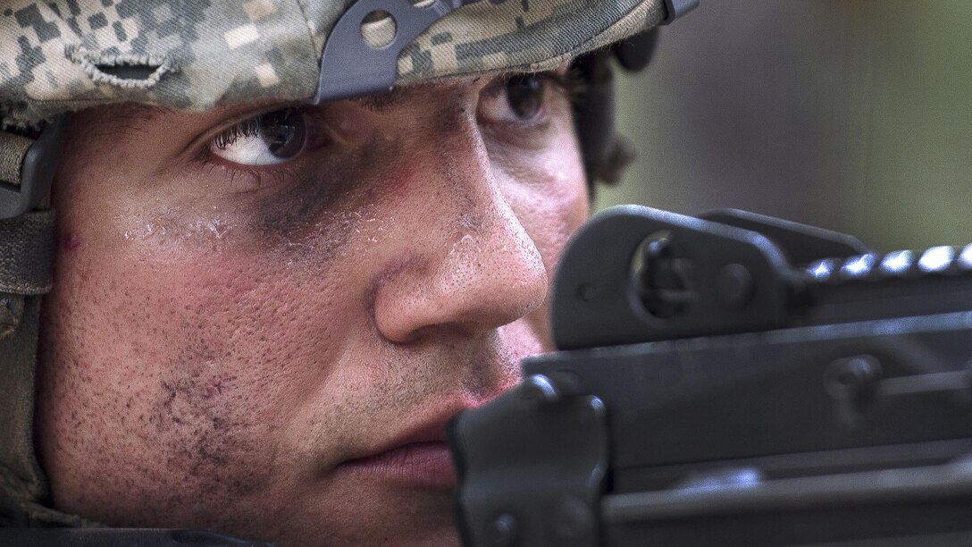 A soldier's face is shown in close up as he aims a weapon.