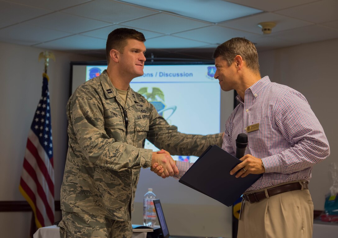 Captain Justin Toney, 20th Space Control Squadron flight commander, receives a letter of appreciation for the breakfast from Robert Kirila.