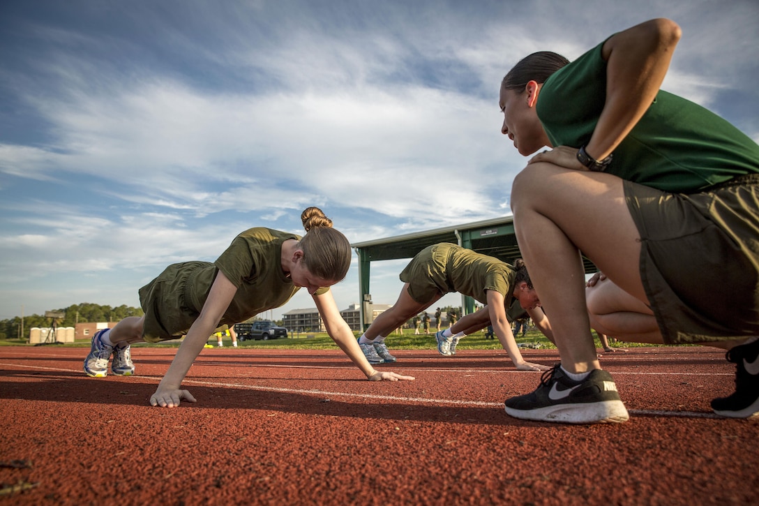 An instructor monitors as Marine Corps recruits do pushups.