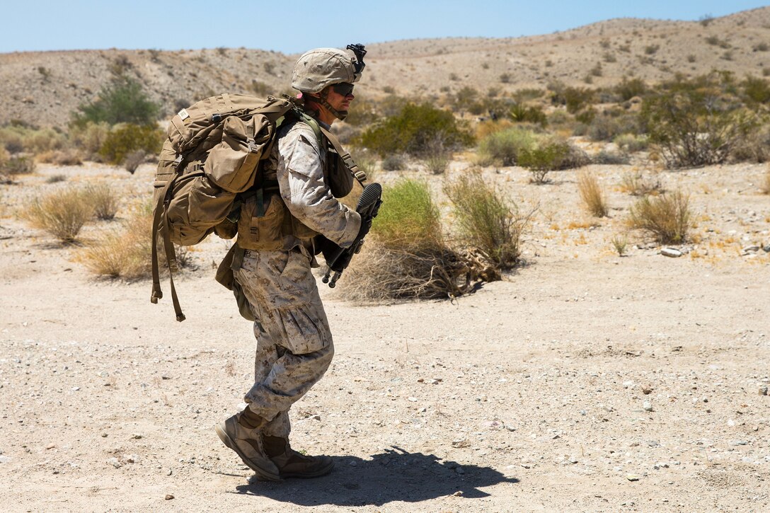 Marines maneuver to a defensive fighting position after conducting air assault training.