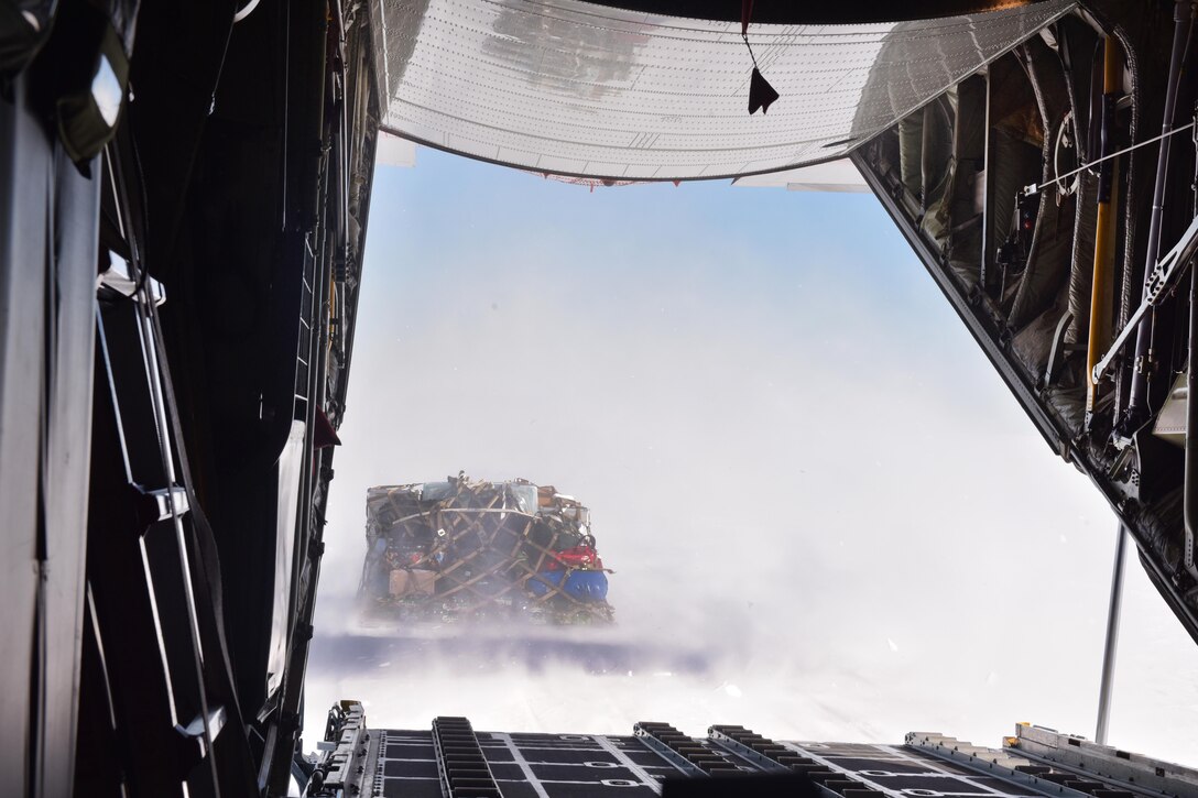 Airmen conduct a combat offload of cargo from a LC-130 Skibird to deliver supplies to scientists at the East Greenland Ice Core Project.