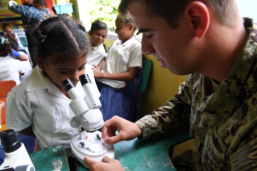 Navy Lt. j.g. Jack Dembowski helps a girl examine a specimen through a microscope during an entomology class at República de Colombia Elementary School in Silin, Honduras, Aug. 1, 2017. Sailors participated in a community relations project as part of Southern Partnership Station 2017, a U.S. Navy deployment focused on subject-matter-expert exchanges with partner-nation militaries and security forces in Central and South America. Navy photo by Petty Officer 1st Class Jeremy Starr