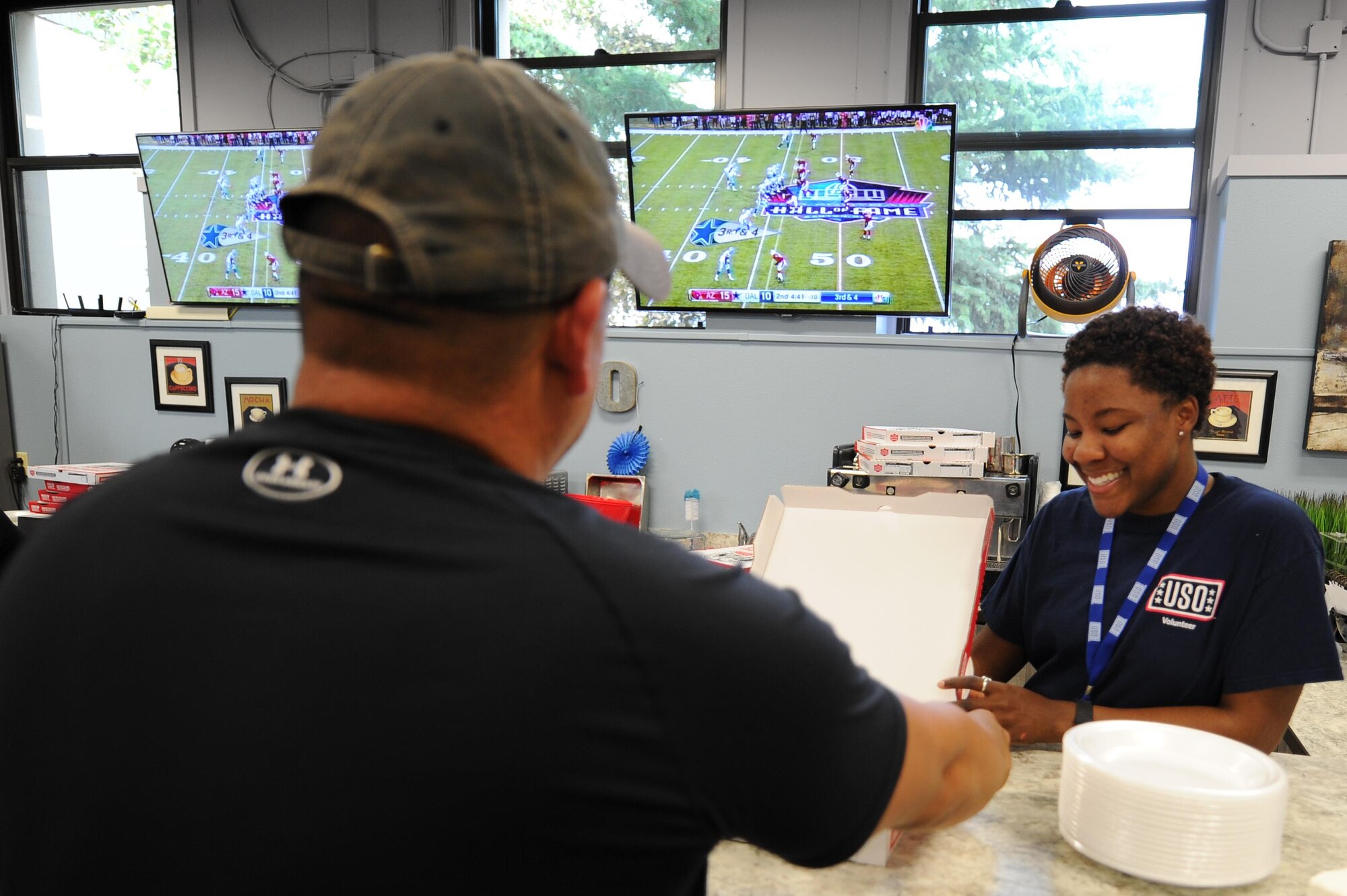 U.S. Air Force Senior Airman Kahdija Slaughter, a 354th Fighter Wing Public Affairs broadcast journalist and USO volunteer, serves a visiting service member a slice of pizza Aug. 3, 2017, at Eielson Air Force Base, Alaska. The USO opened for the Pro Football Hall of Fame Game 2017 and provided free pizza. (U.S. Air Force photo by Airman 1st Class Eric M. Fisher)