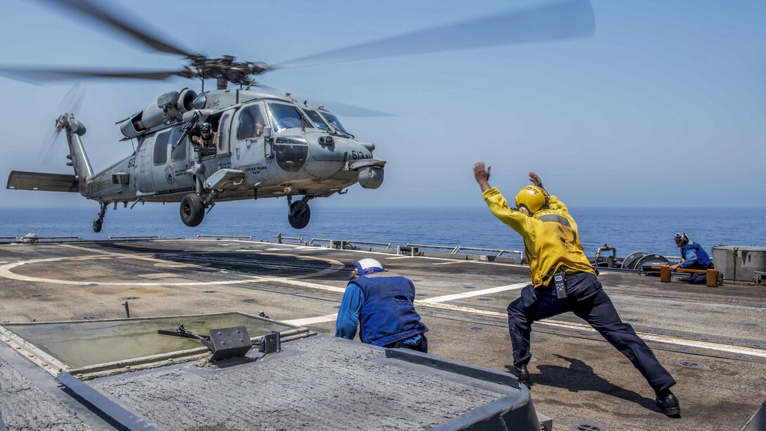 A sailor directs a helicopter during takeoff from a ship in the Arabian Gulf.