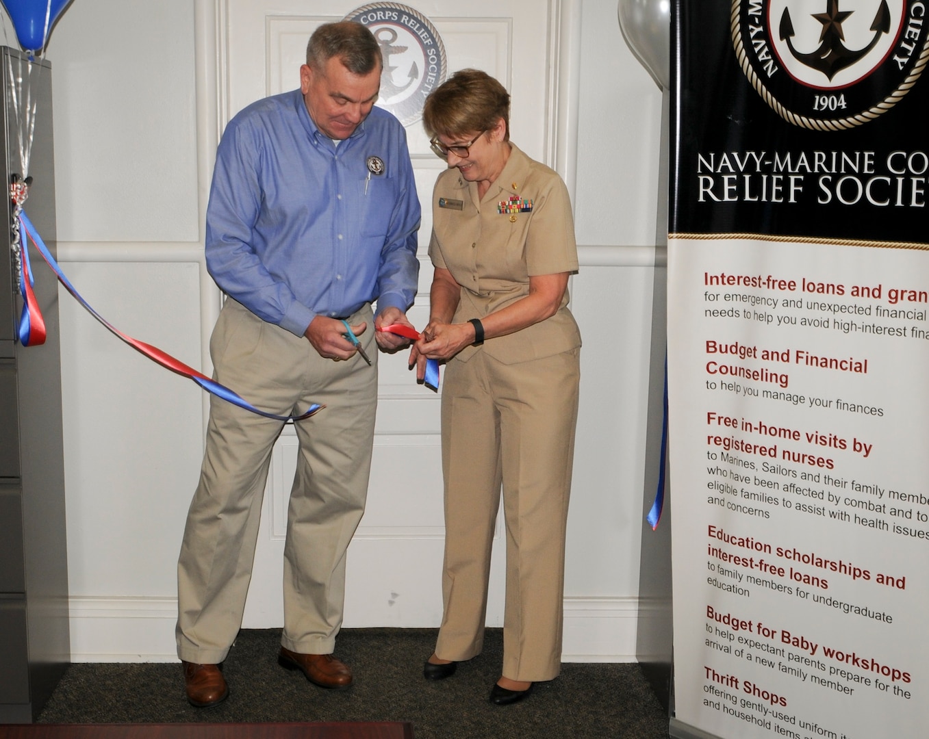 Retired Marine Corps Brig. Gen. Peter Collins (left), Navy-Marine Corps Relief Society (NMCRS) chief operations officer, and Rear Adm. Rebecca McCormick-Boyle, commander, Navy Medicine Education, Training and Logistics Command, and senior Navy officer in San Antonio, cut a ceremonial ribbon at the NMCRS San Antonio branch on board Joint Base San Antonio - Fort Sam Houston. NMCRS opened up a small, limited-functioning office in San Antonio in January 2015 but has grown with the Navy population in the area and just celebrated the opening of a full-service branch.