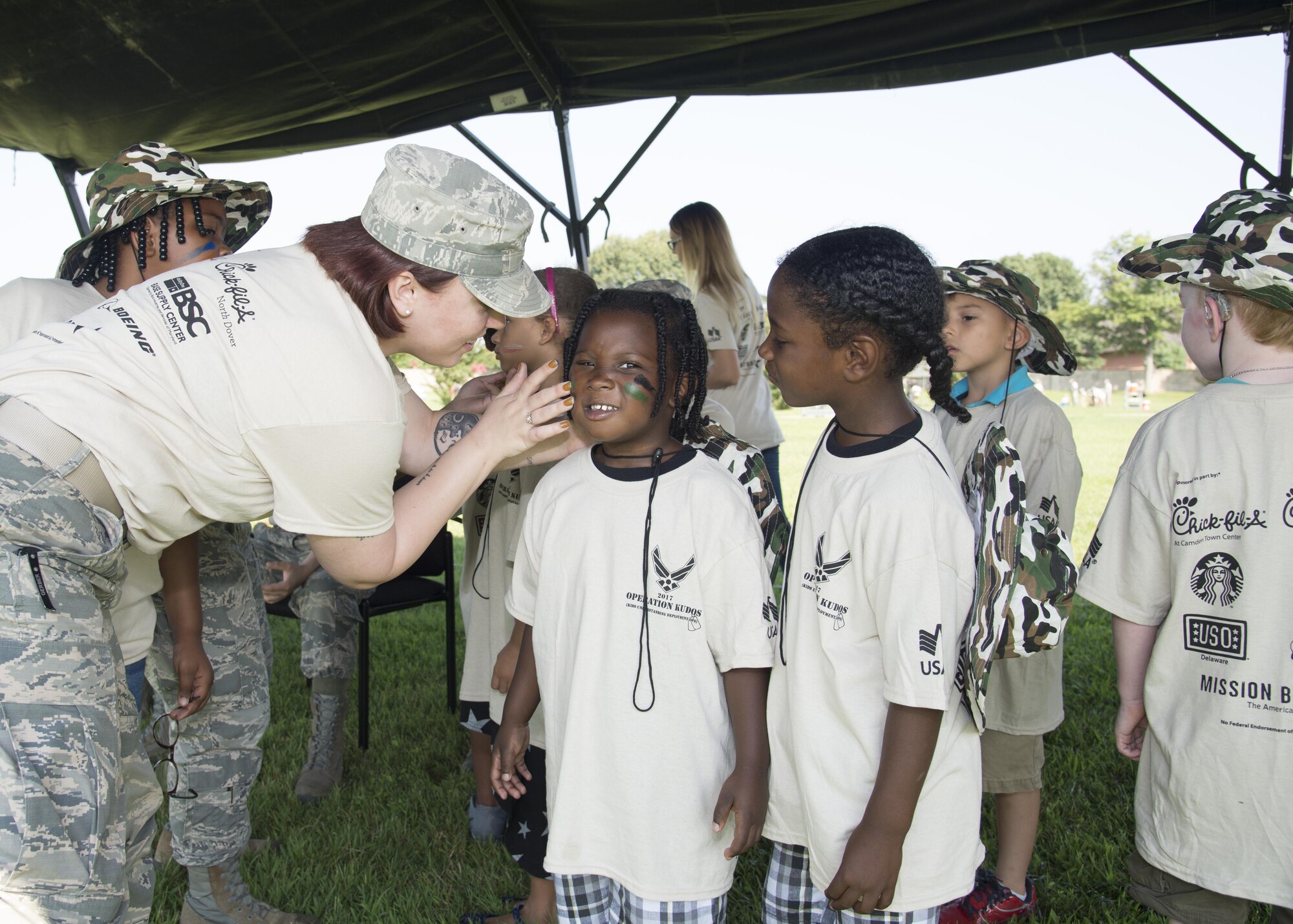Staff Sgt. Courtney Nameth, 436th Airlift Wing administrative support, paints the face of a child participating in Kids Understanding Deployment Operations Aug. 3, 2017, at the Youth Center on Dover Air Force Base, Del. Nameth and other volunteers helped paint the faces of children on each of the nine chalks that simulated the deployment process. (U.S. Air Force photo by Staff Sgt. Jared Duhon)