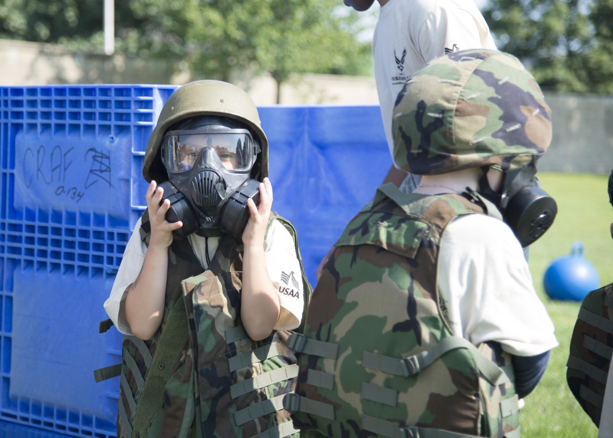 A child dressed in a gas mask and body armor checks his seal during the Kids Understanding Deployment Operations Aug. 3, 2017, at the Youth Center on Dover Air Force Base, Del. Gear was brought out by various base organizations to help children understand what their parents might experience during a deployment. (U.S. Air Force photo by Staff Sgt. Jared Duhon)