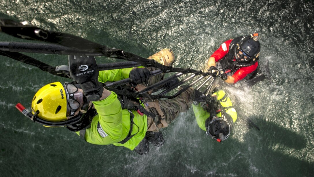 Three airmen climb a ladder out of the water.