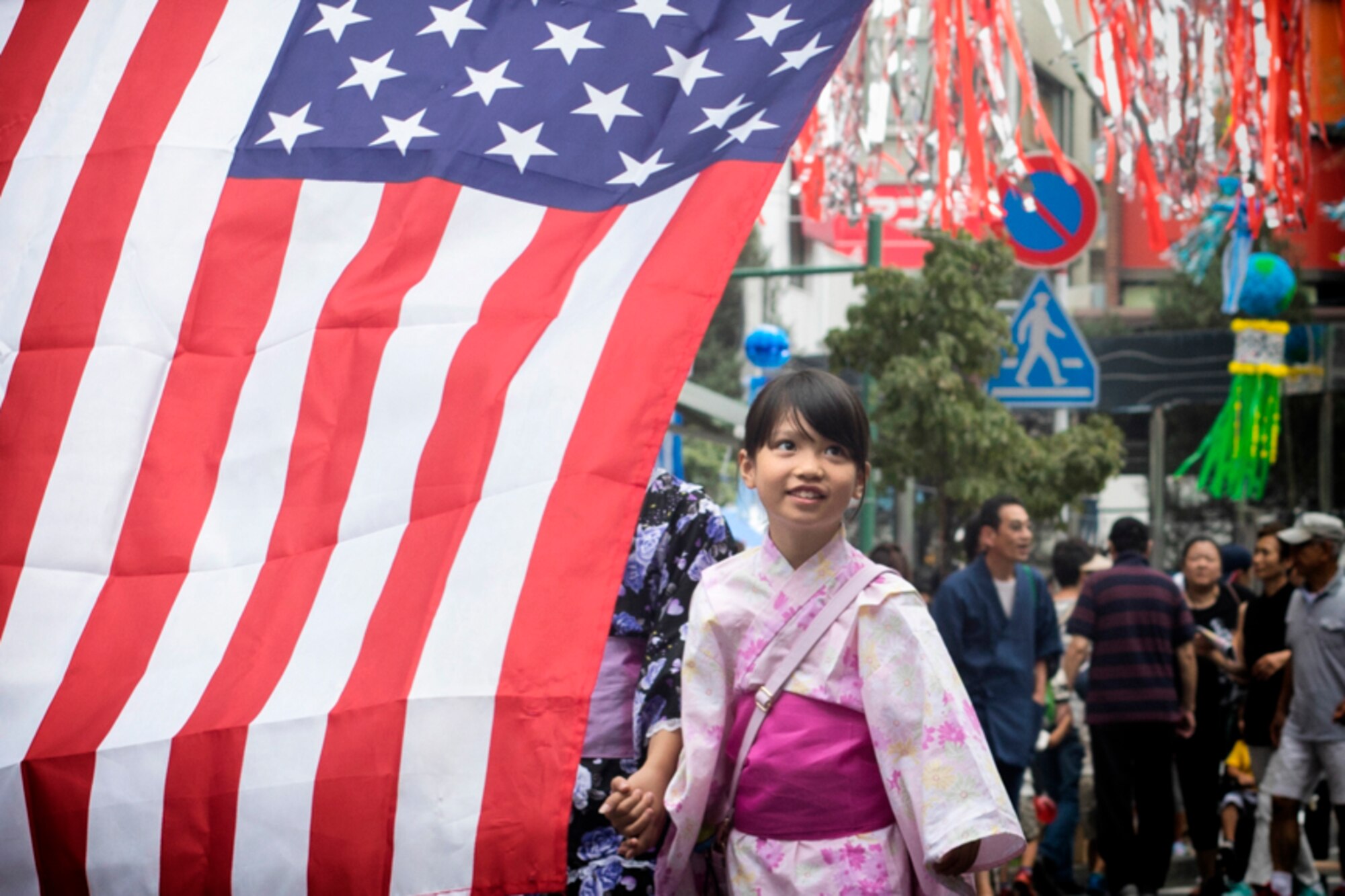 A girl wearing a traditional Yukata walks on a street decorated with mixture of American and Japanese ornaments