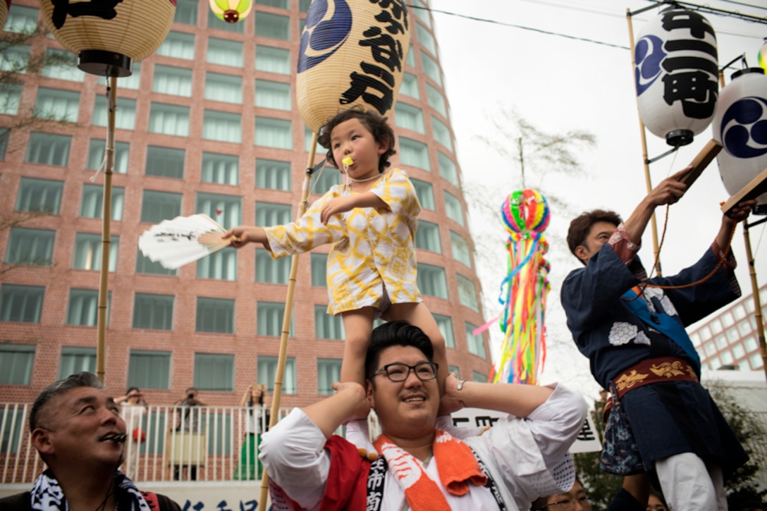 A child helps direct people carrying a mikoshi