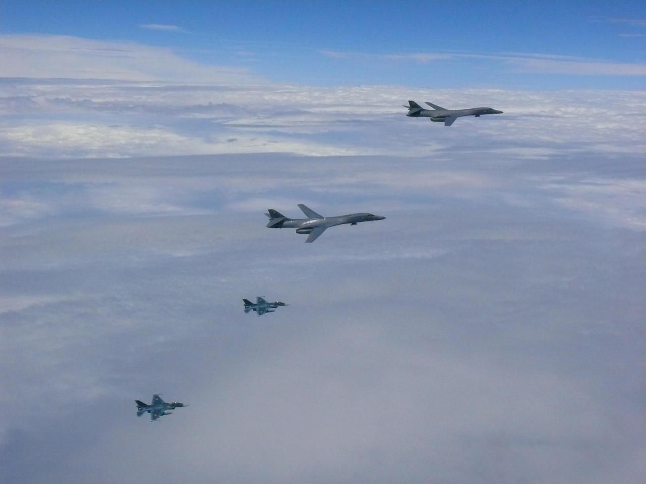 Four planes fly above clouds.