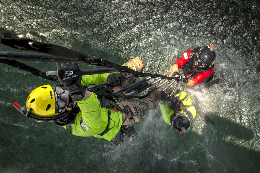 Three airmen climb a ladder out of the water.