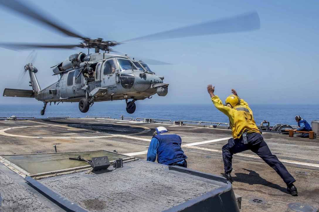 A sailor directs a helicopter during takeoff from a ship in the Arabian Gulf.