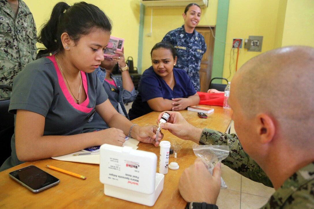 U.S. Navy Lt. Cmdr. Ian Sutherland, technical director for the Navy Entomology Center of Excellence, shows local doctors and nurse how to test mosquitoes for diseases