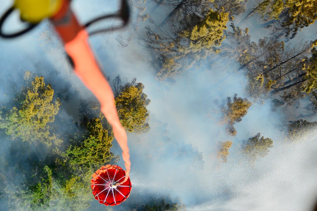 A bambi bucket dumps water on a wildfire.