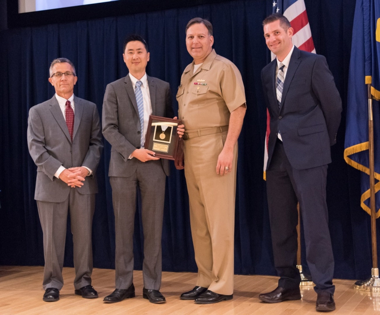 Ji Kim, deputy comptroller for Carderocks budget office, receives the Rear Adm. Grace M. Hopper Award for excellence in organizational support at the Naval Surface Warfare Center, Carderock Division Honor Awards ceremony Aug. 1, 2017, in West Bethesda, Md. From left to right: Technical Director Dr. Tim Arcano, Kim, Commanding Officer Capt. Mark Vandroff and Comptroller Eric Stone. (U.S. Navy photo by Jake Cirksena/Released)