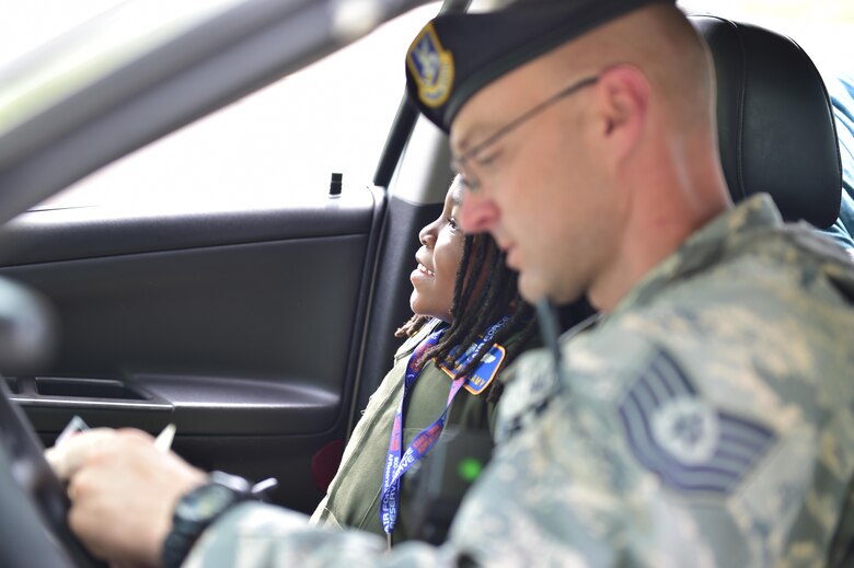 Tech. Sgt. John Hall, a fire team member with the 910th Security Forces Squadron here, writes a citation during a staged traffic stop with nine-year-old Donovan Bellamy assisting in the passenger seat, Aug. 7, 2017.