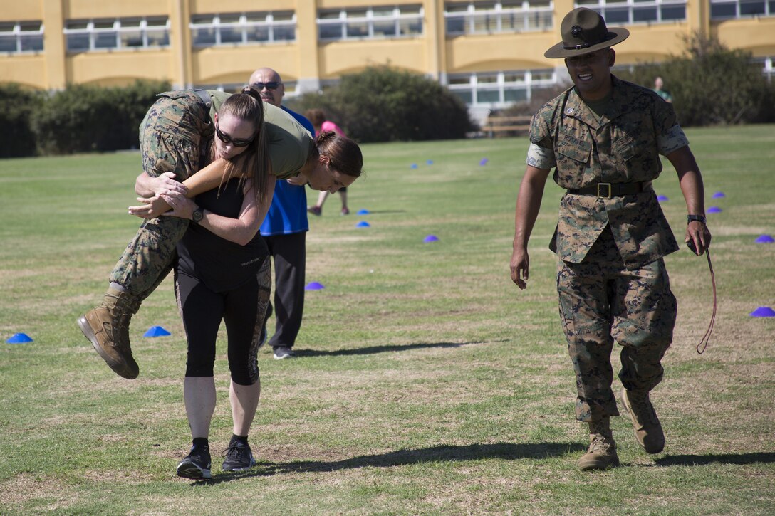 Aime Dugger, a teacher at Garland High School in Garland, TX, conducts a fireman carry during the maneuver under fire portion of the combat fitness test at Marine Corps Recruit Depot San Diego, August 8, 2017. The workshop is a four-day program designed to better inform high school and college educators about the benefits and opportunities available during service in the Marine Corps. This allows the attendees to return to their place of business and provide firsthand experience and knowledge with individuals interested in military service.