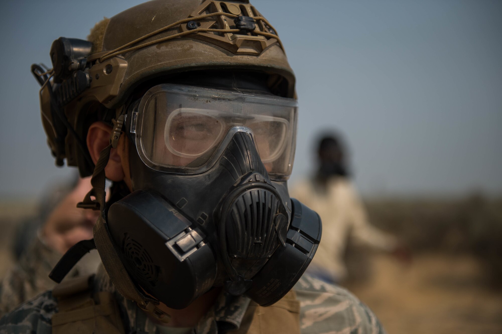 Staff Sgt. Alvin Ly, 921st Contingency Response Squadron defender, looks on as Airmen dawn their M50 Gas Mask, during exercise Mobility Guardian at Moses Lake, Wash., Aug.8, 2017.  Approximately 650 international service members will work alongside more than 3,000 U.S. service members during Mobility Guardian.  The exercise is Air Mobility Command’s premier readiness exercise, providing an opportunity for the Mobility Air Forces to train with joint and international partners in airlift, air refueling, aeromedical evacuation and mobility support.  (U.S. Air Force photo by Staff Sgt. Robert Hicks)