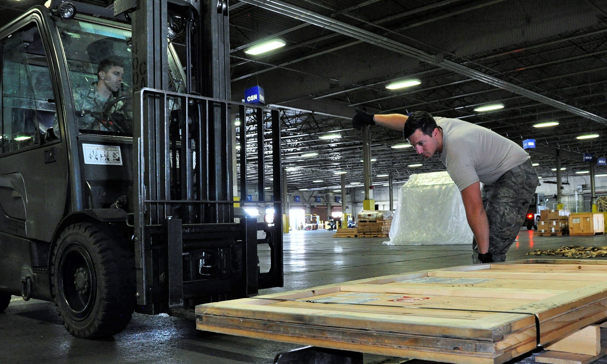 Senior Airman David Stevens, 60th Aerial Port Squadron, directs Senior Airman Nathan Jarvis, a 39th APS cargo processing technician and traditional reservist, on the use of a forklift as Jarvis manipulates heavy cargo at Travis Air Force Base, Calif., July 11, 2017.