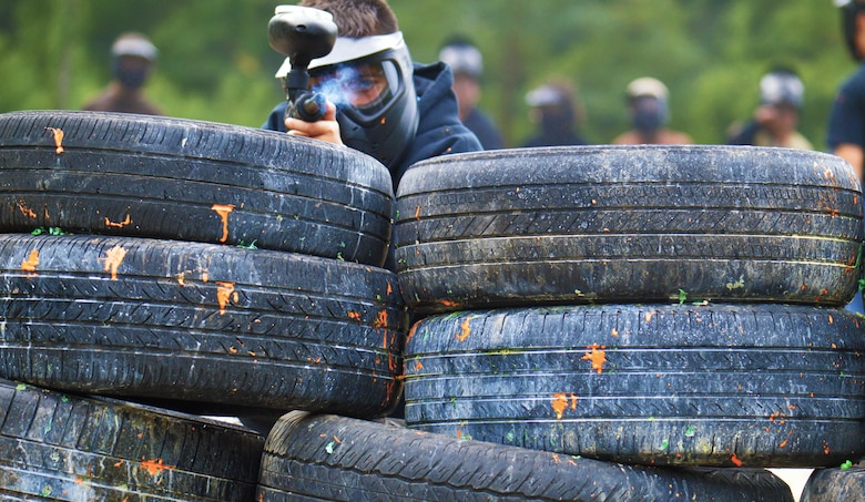 Teenager takes cover behind tires at the Combat Town course at Marin Corps Base Quantico Paintball Park.