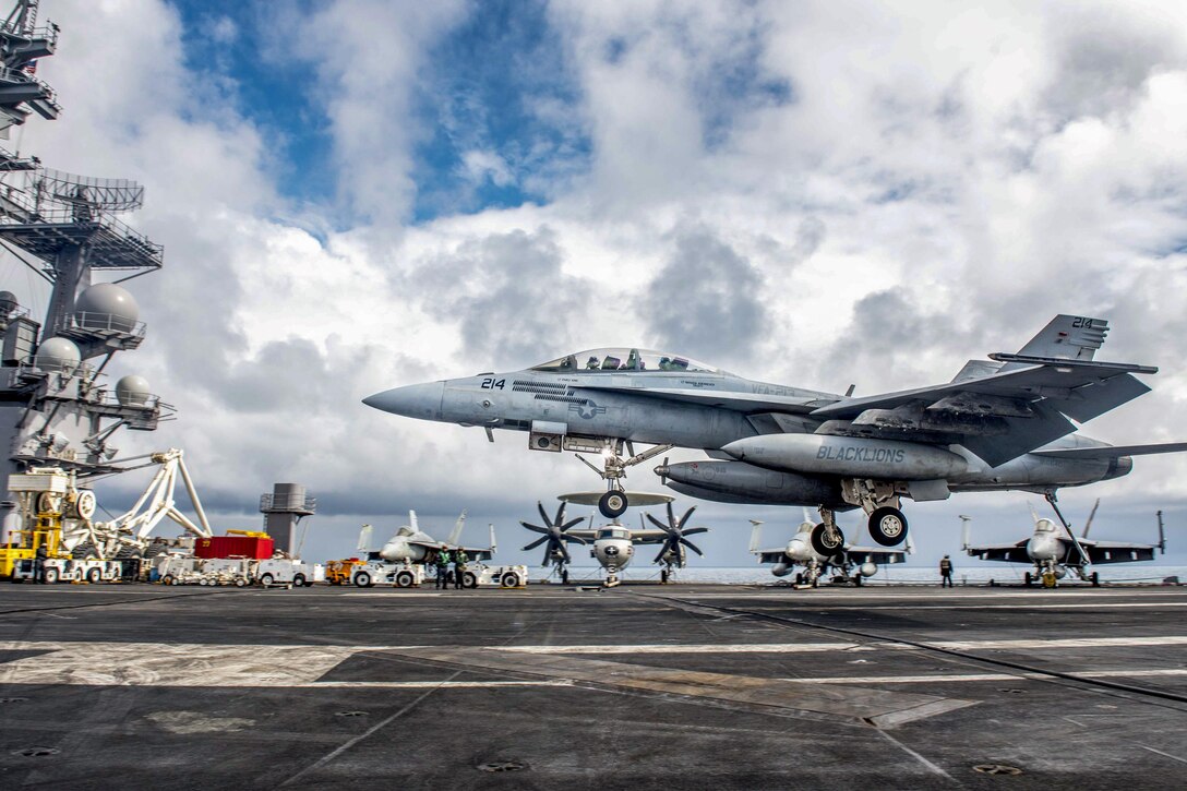 An aircraft lands on a ship's flight deck.