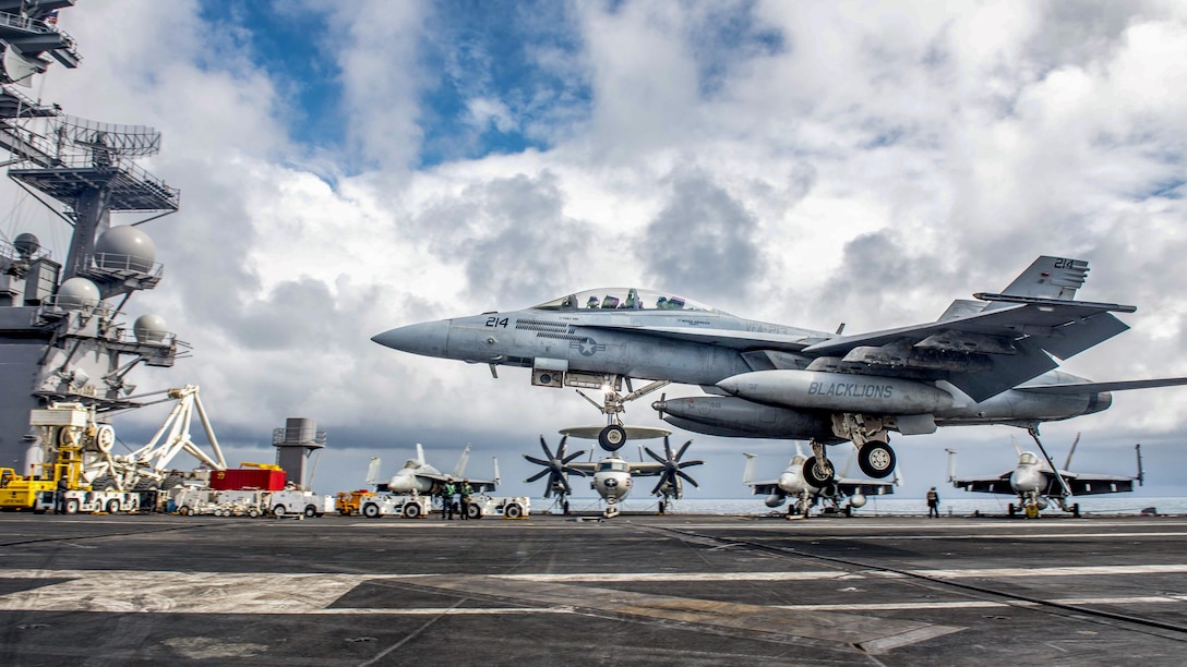 An aircraft lands on a ship's flight deck.