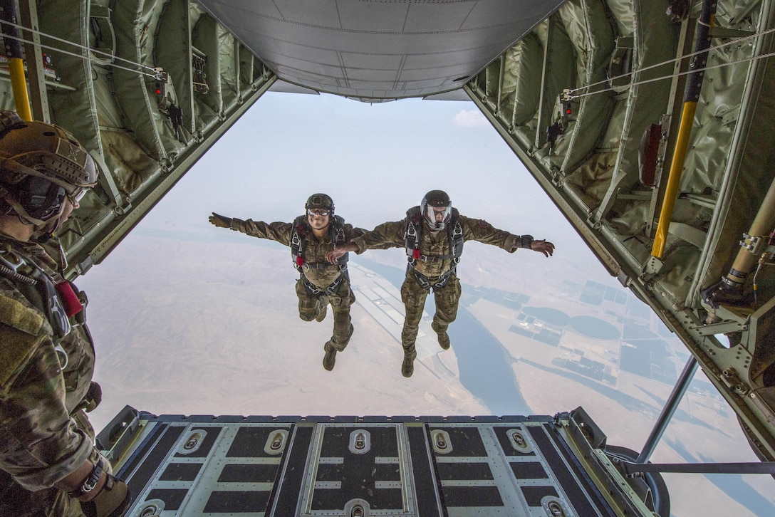 Two airmen are suspended side-by-side in the air after jumping from an aircraft.