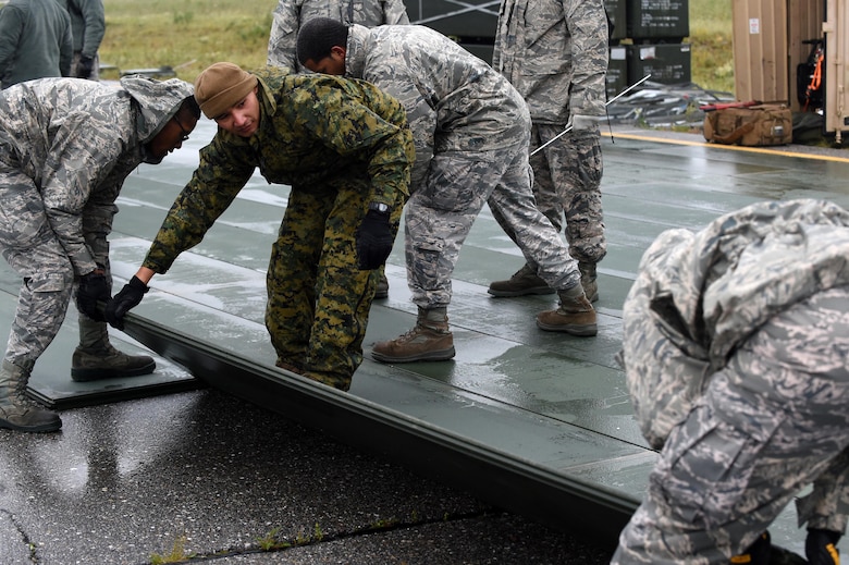 U.S. Marine Corps members with the 3rd Marine Aircraft Wing train Air Force Airmen on how to lay AM 2 matting down on damaged flight lines during exercise Arctic ACE, Alaska, July 11, 2017. The exercise included Airmen from the 3rd Wing, 673rd Air Base Wing, and 644th Combat Communications Squadron from Andersen, Air Base, Guam, as well as Marines from the 3rd Marine Aircraft Wing and U.S. Army in Alaska Soldiers, and focused on validating new ways to deploy and maneuver assets more fluidly during a crisis or conflict.