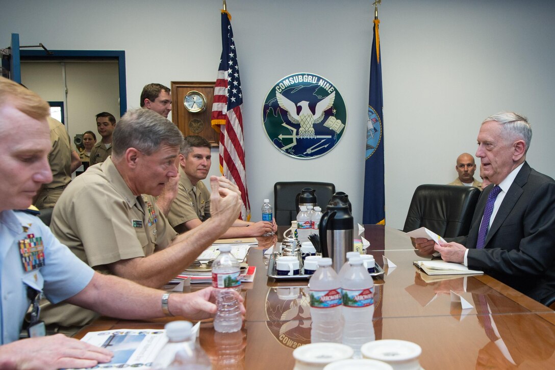 Defense Secretary Jim Mattis talks at a table with naval personnel.