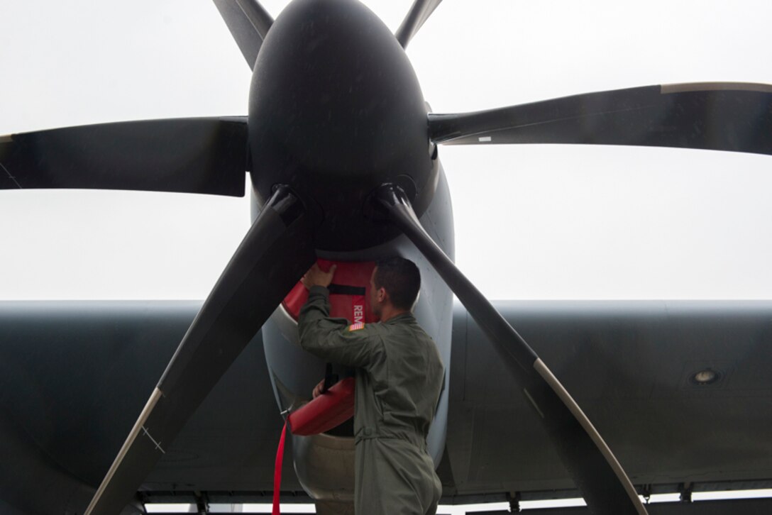 alt=Staff Sgt. Christopher Rivera, 374th Aircraft Maintenance Squadron flying crew chief, inserts engine intake covers into a C-130J Super Hercules