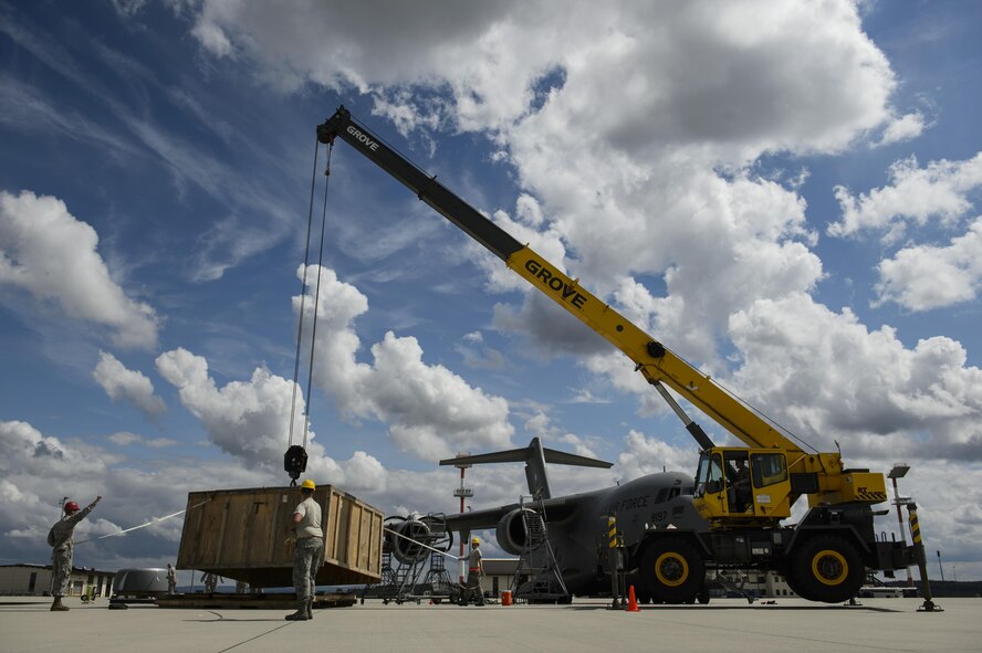 Airmen from the 726th Air Mobility Squadron work with 52nd Civil Engineer Squadron Dirt Boyz to move parts for replacing an engine on a C-17 Globemaster III at Spangdahlem Air Base, Germany, Aug. 9, 2017. The 726th AMS worked with the 52nd Logistics Readiness Squadron vehicle operations, 52nd CES Dirt Boyz, and 721st Aircraft Maintenance Squadron in support of fixing the engine which takes an average of 12 hours to complete. (U.S. Air Force photo by Staff Sgt. Jonathan Snyder)