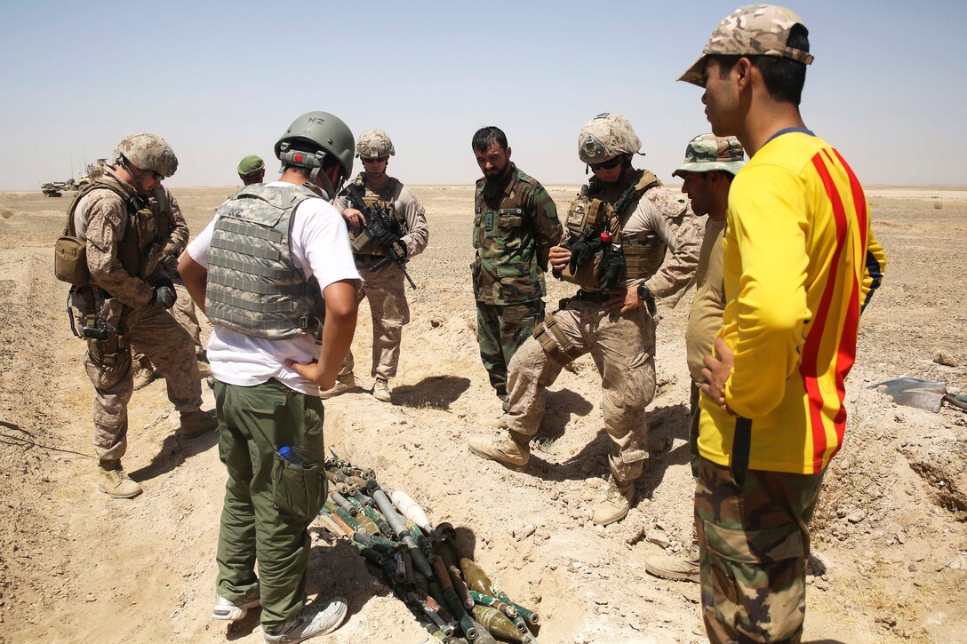 A U.S. Marine discusses disposal processes with Afghan national army explosive ordnance soldiers.