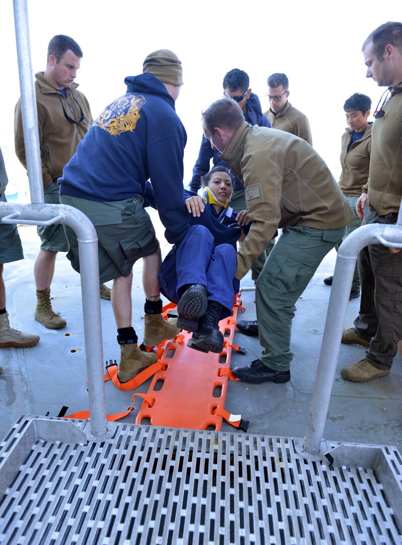Petty Officer 1st Class Kim Nguyen (center) participates in a joint U.S. Coast Guard – U.S. Navy emergency plan extraction drill aboard the Coast Guard Cutter Healy in which the dive teams practice for and evaluate different cold water dive scenarios, July 22, 2017.  The Coast Guard’s dive team depends on the Navy for use of their dive recompression chamber, a tool that helps to treat diving-related trauma. U.S. Coast Guard photo by Senior Chief Petty Officer Rachel Polish