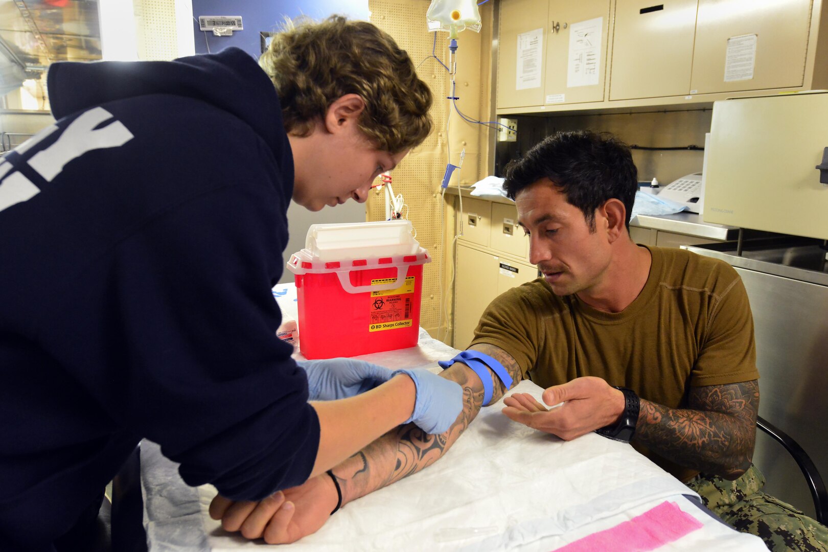 Coast Guard Petty Officer 3rd Class Shannon Eubanks, a boatswains mate onboard the Coast Guard Cutter Healy, places an IV on Navy Petty Officer 1st Class Richard Dutton, a member of a joint Coast Guard – Navy dive team deployed on the Healy, during training, July 27, 2017. Coast Guard divers continually train to provide basic medical aid to meet the subsurface needs of the service. U.S. Coast Guard photo by Petty Officer 2nd Class Meredith Manning