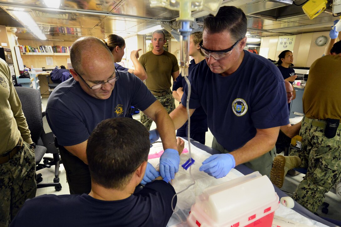 Navy Senior Chief Petty Officer Randle Groves and Coast Guard Chief Petty Officer Chuck Ashmore, members of a joint Coast Guard – Navy dive team deployed on the Coast Guard Cutter Healy, place an IV during medical training, July 27, 2017. While underway during the Healy’s Arctic patrol, Coast Guard divers will conduct cold water ice dive training with support from the Navy’s recompression chamber team and an independent duty corpsman/dive medical technician. U.S. Coast Guard photo by Petty Officer 2nd Class Meredith Manning