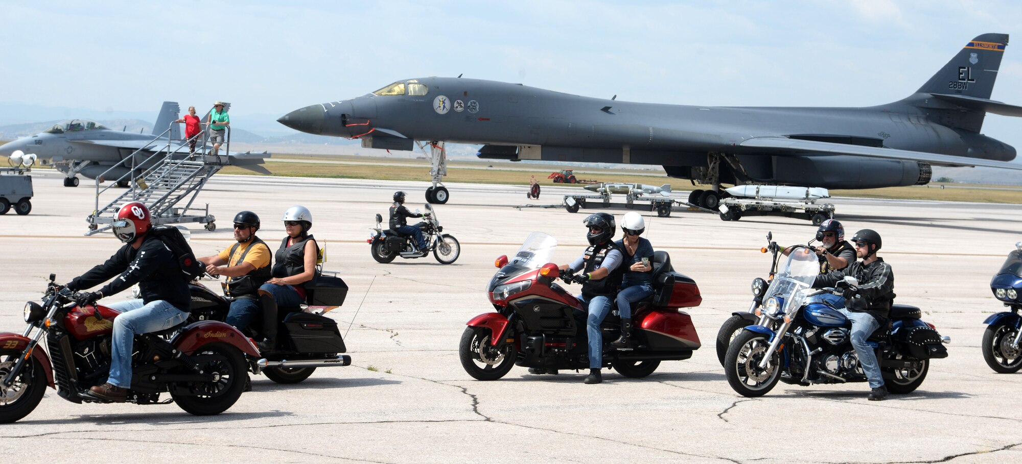 Motorcyclists pass by a B-1 bomber and an F-18 Super Hornet Aug 8, 2017 on the flight line at Ellsworth Air Force Base, S.D. The motorcycle ride ended at the Sturgis Veterans Appreciation Ceremony followed by with a flyover from a B-1 bomber over Main Street. (U.S. Air Force photo by Airman 1st Class Thomas Karol)