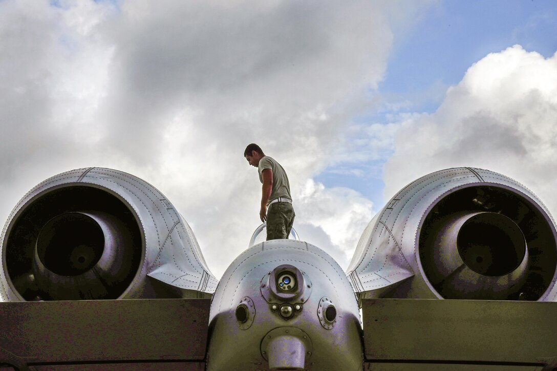An airman walks on top of an aircraft.