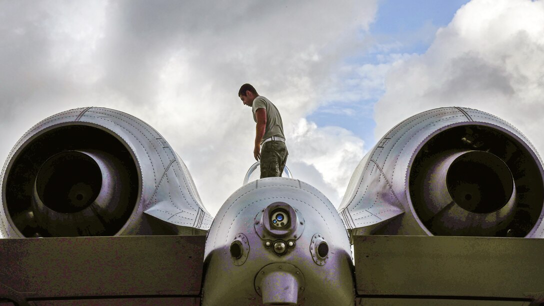 An airman walks on top of an aircraft.