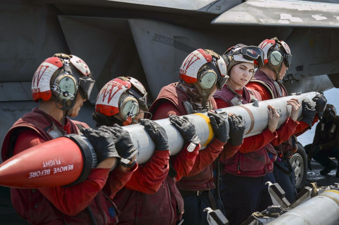 Sailors carry a missile on a ship.