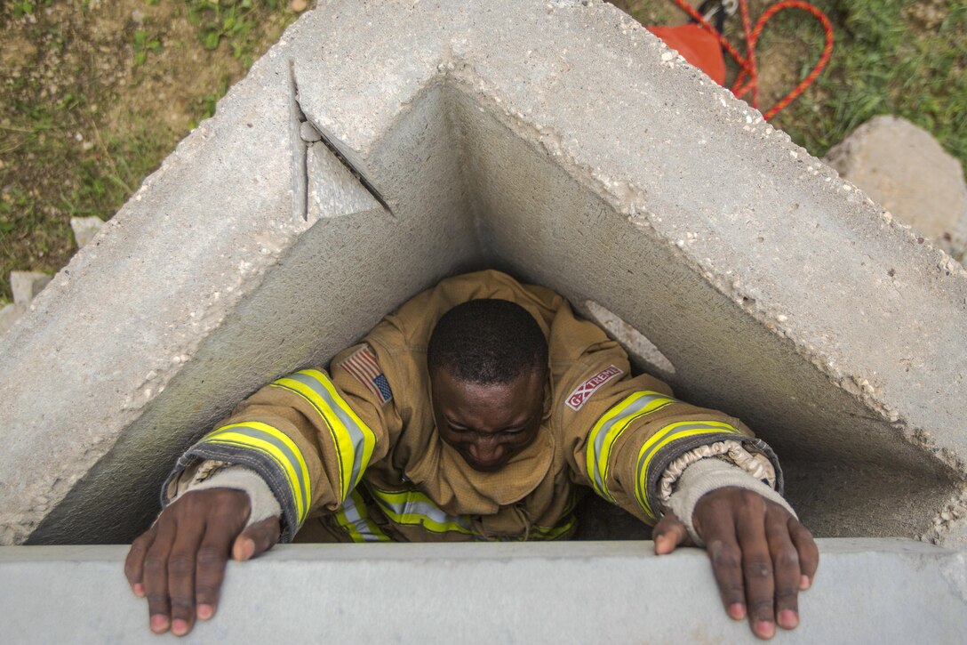 A soldier tries to climb out of a triangle-shaped cement tunnel.