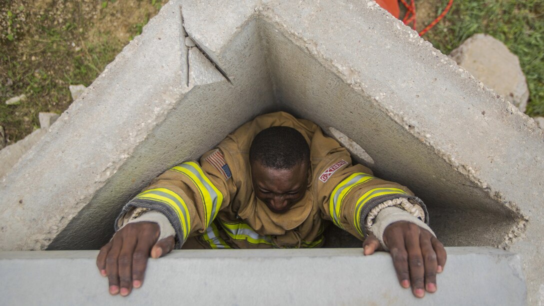 A soldier tries to climb out of a triangle-shaped cement tunnel.