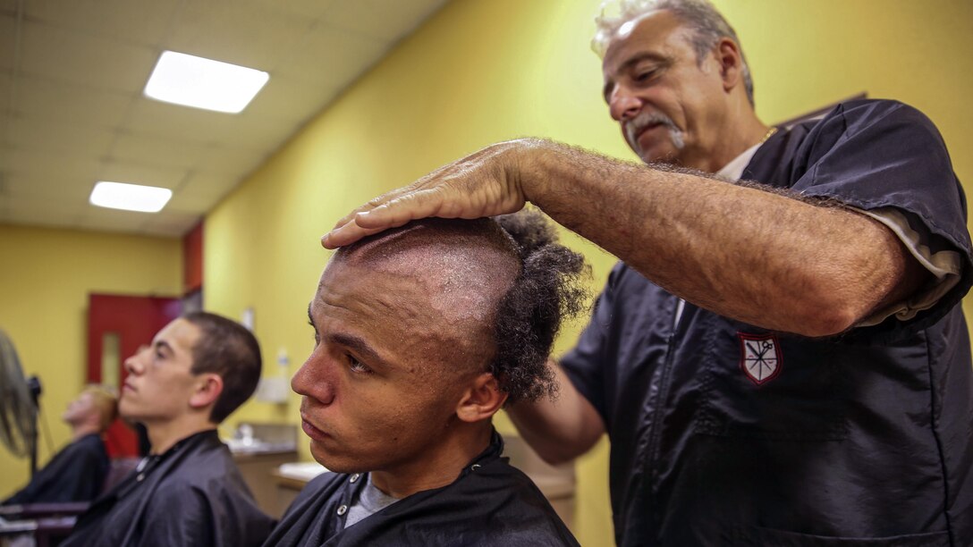 A Marine Corps recruit has his head shaved.