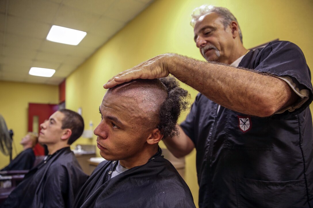 A Marine Corps recruit has his head shaved.