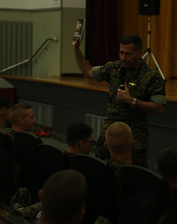 Sgt. Maj. Anthony Spadaro holds up “The Warrior Ethos” encouraging service members to read it to help understand who they are and where they want to be in life at a briefing  Aug. 10 in the base theater aboard Camp Foster, Okinawa, Japan.