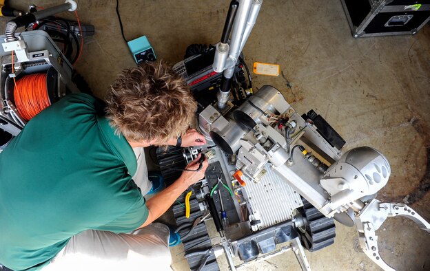 Kimberly Tipton, Remotec instructor, troubleshoots an Air Force Medium Sized Robot at Kunsan Air Base, Republic of Korea, Aug. 10, 2017. Remotec, which supplies and maintains AFMSRs and other robots for the Air Force, is a company based in Clinton, Tenn. specializing in mobile robot systems for hazardous-duty operations. (U.S. Air Force photo by Senior Airman Colby L. Hardin)