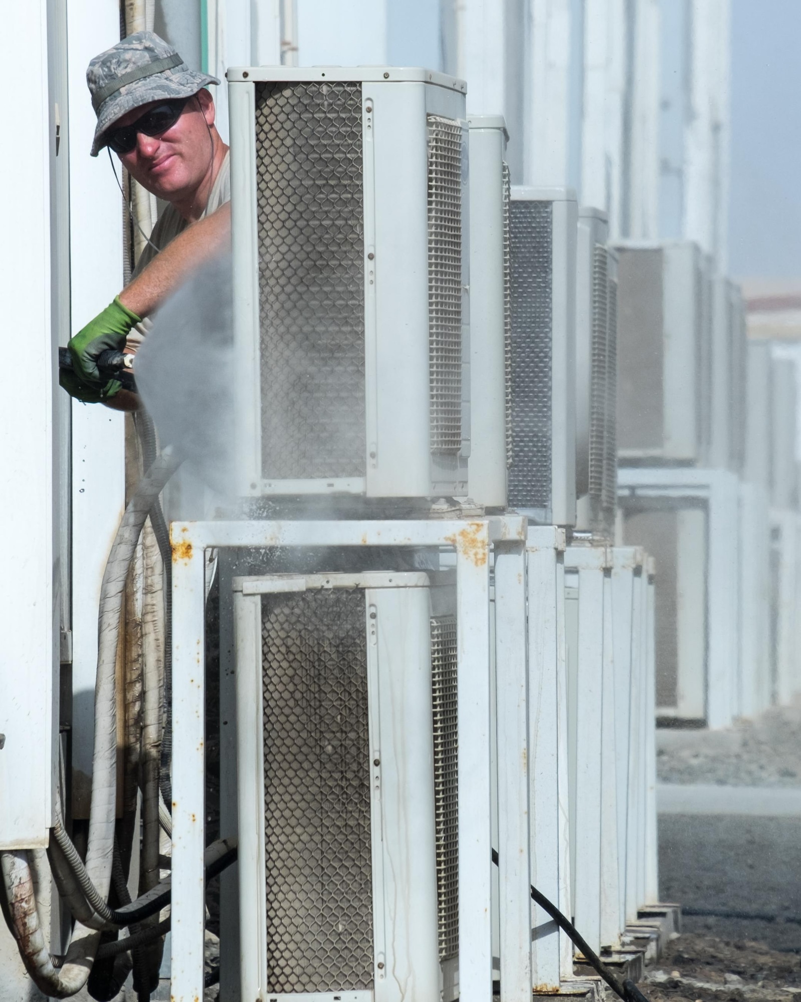Senior Airman Thomas, 380th Expeditionary Civil Engineer Squadron heating, ventilation, and air conditioning technician, washes air conditioner condenser coils August 8, 2017, at Al Dhafra Air Base, United Arab Emirates.