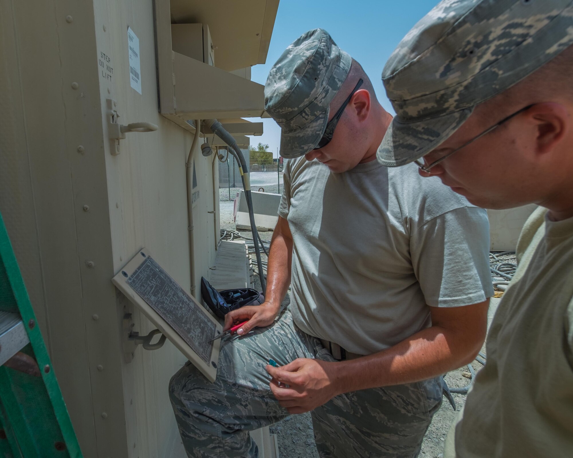 Staff Sgt. Zachery, left, and Senior Airman Timothy, both 380th Expeditionary Civil Engineer Squadron heating, ventilation, and air conditioning technicians, examine a wiring diagram August 8, 2017, at Al Dhafra Air Base, United Arab Emirates.