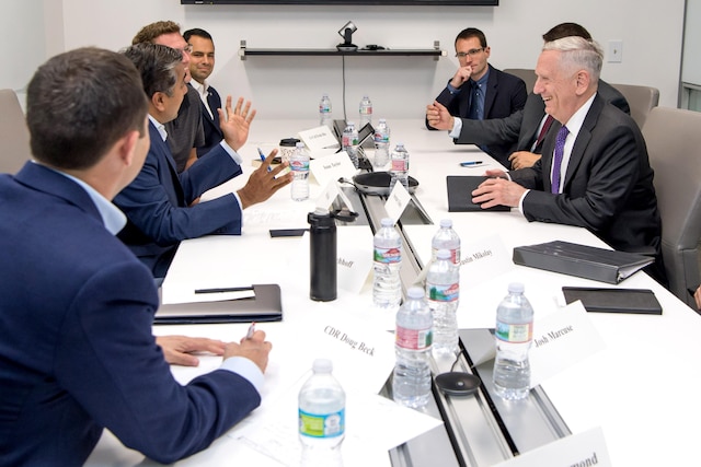 Defense Secretary Jim Mattis speaks to a group of people at a table.
