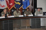 Four generals seated at table, facing viewer.